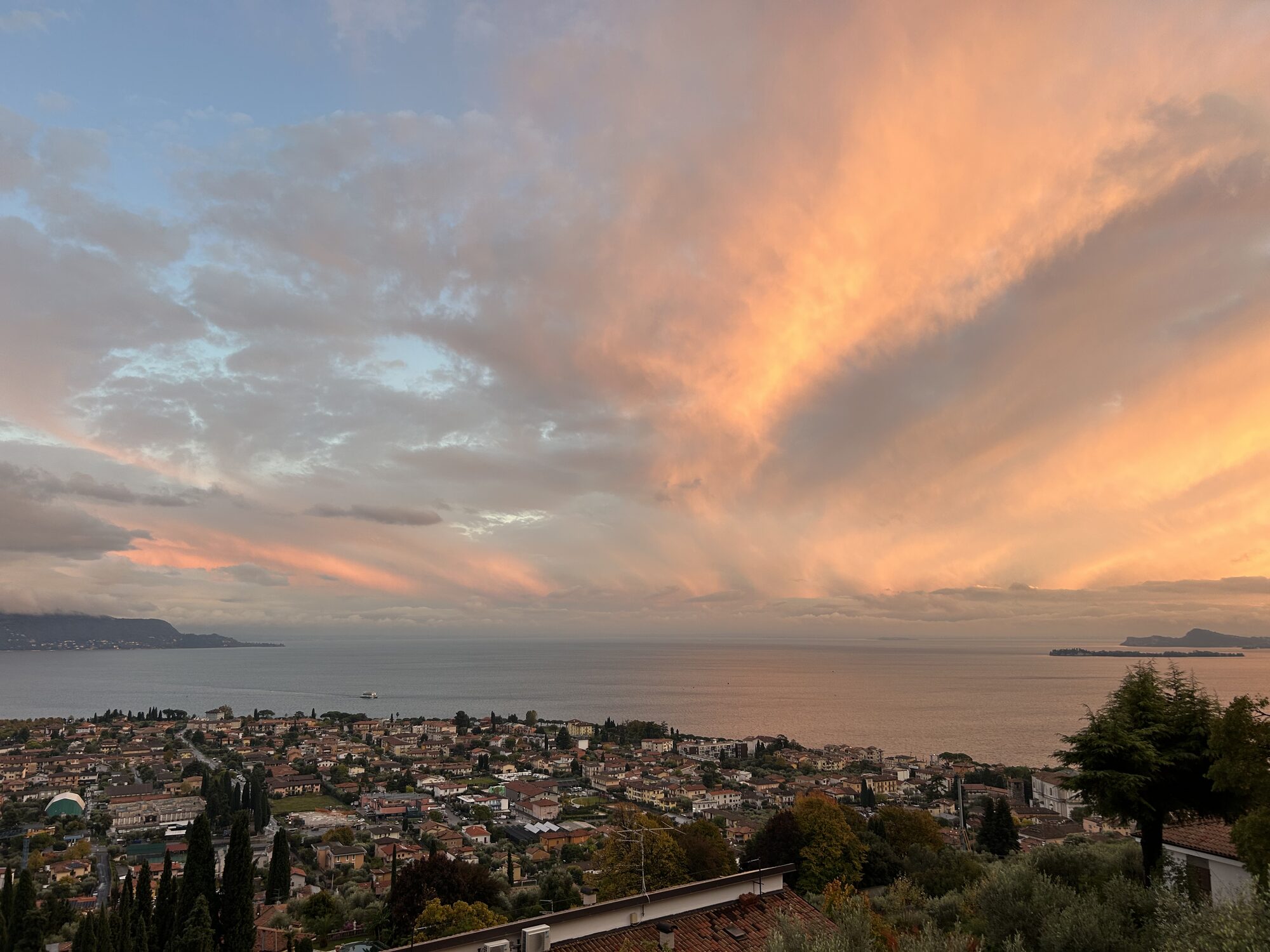 Sonnenuntergang mit dramatischem Wolkenhimmel über einer Ortschaft am Gardasee